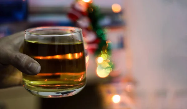 a glass of alcohol whisky held in hand with background blur bokeh lights