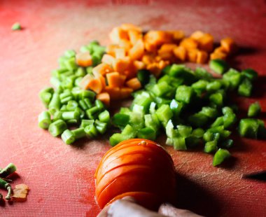 kırmızı biber domates ve havuç küçük parçalar halinde kesilmiş, ince doğranmış sebze bir doğrama tahtası üzerinde