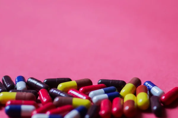 Heap of capsules in pink background with space for text — Stock Photo, Image