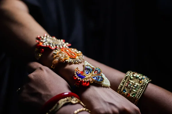 hand of a lady tying rakhi in hand of a guy during the hindu ritual of rakshabandhan with selective focus