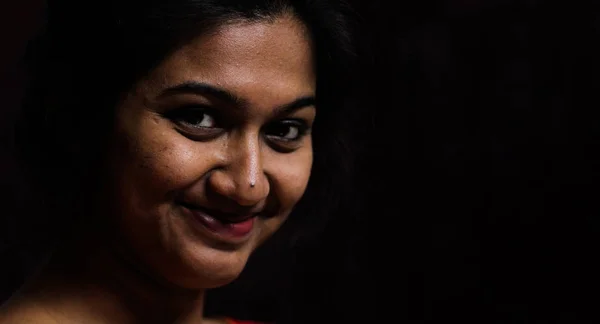 Μια ινδική γυναίκα κοιτάζοντας και χαμογελώντας στην κάμερα σε μαύρο φόντο — Φωτογραφία Αρχείου