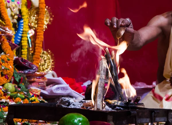 Mão de um padre adorando deus hindu com fogo e yagna ritual, adicionando combustível em chamas — Fotografia de Stock