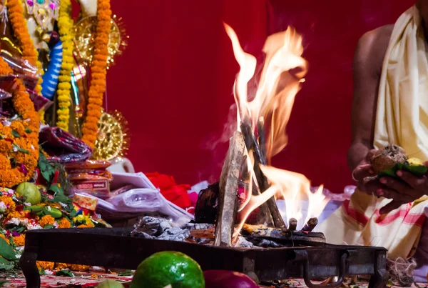 Mão de um padre adorando deus hindu com fogo e yagna ritual, adicionando combustível ghee em chamas — Fotografia de Stock