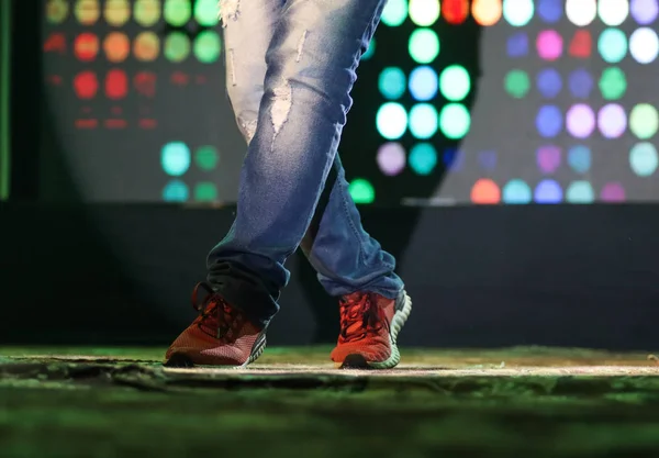 Pies de un bailarín en el escenario haciendo hip hop postura de baile con luces de neón de fondo —  Fotos de Stock