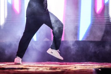 arka plan neon ışıkları ile hip hop dans duruş yapıyor sahnede bir dansçı ayakları