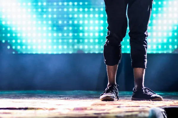 Pieds d'un danseur sur scène faisant position de danse hip hop avec des lumières au néon de fond — Photo