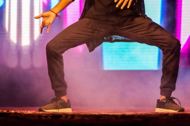 arka plan neon ışıkları ile hip hop dans duruş yapıyor sahnede bir dansçı ayakları