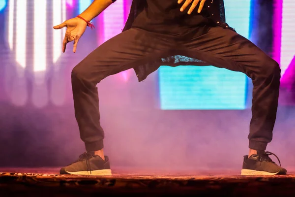 Pies de un bailarín en el escenario haciendo hip hop postura de baile con luces de neón de fondo —  Fotos de Stock