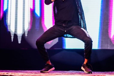 arka plan neon ışıkları ile hip hop dans duruş yapıyor sahnede bir dansçı ayakları