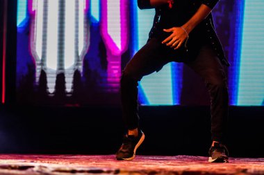 arka plan neon ışıkları ile hip hop dans duruş yapıyor sahnede bir dansçı ayakları