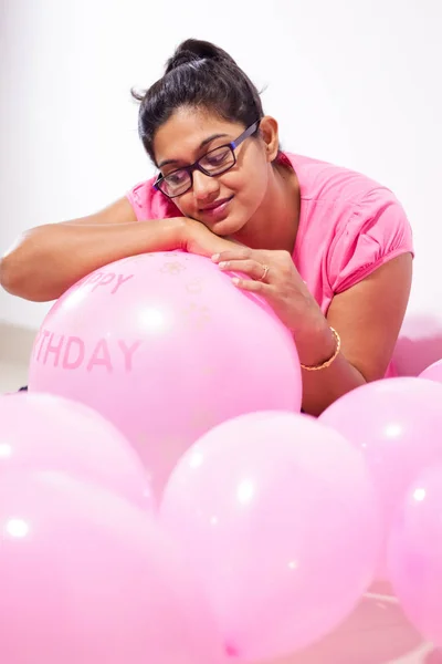 portrait of an indian girl dressed in pink dress with pink balloons on her birthday with selective focus on balloon