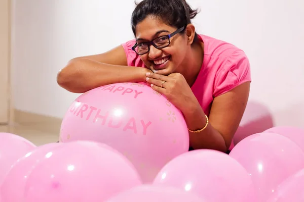 portrait of an indian girl dressed in pink dress with pink balloons on her birthday with selective focus on balloon