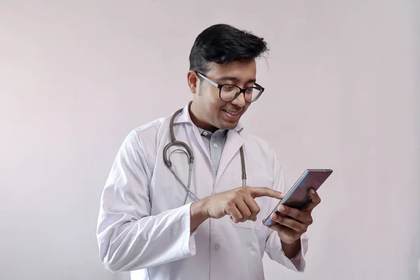 Maschio medico indiano in cappotto bianco e stetoscopio toccare smart phone — Foto Stock