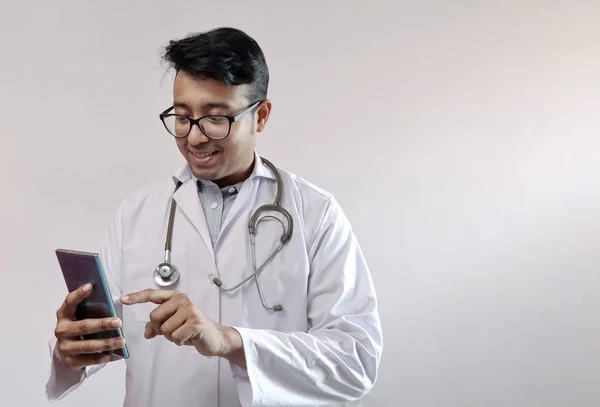 Maschio medico indiano in cappotto bianco e stetoscopio toccare smart phone — Foto Stock