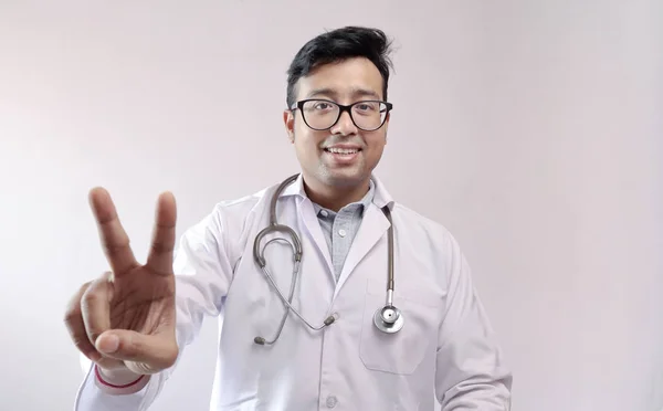 Médecin indien masculin en manteau blanc et stéthoscope montrant signe de victoire en toute confiance — Photo