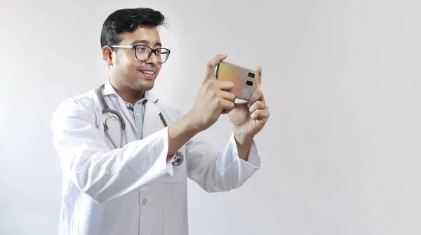 male indian doctor in white coat and stethoscope clicking photo
