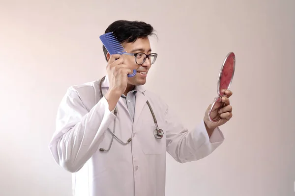 Doctor indian de sex masculin în blană albă și stetoscop pieptănând părul uitându-se la oglindă — Fotografie, imagine de stoc
