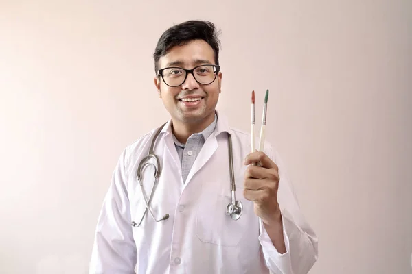 Male indian doctor in white coat and stethoscope with paint brush — Stock Photo, Image
