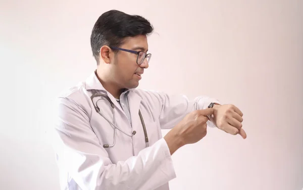 Male indian doctor in white coat and stethoscope adjusting time in smart watch — Stock Photo, Image