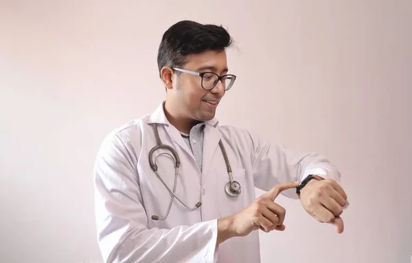 Male indian doctor in white coat and stethoscope touch screen and checking notification in smart watch — Stock Photo, Image