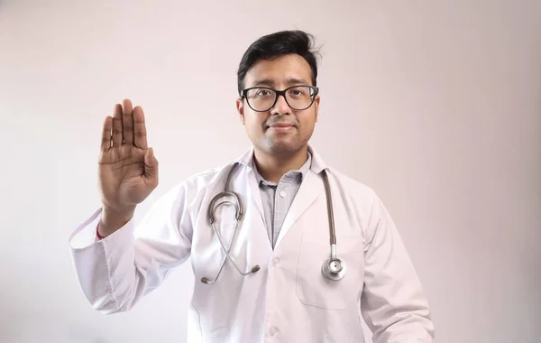 Indischer Arzt in weißem Mantel und Stethoskop schwört hippokratischen Eid Stockbild