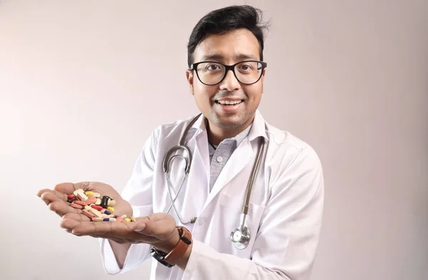 Индийский врач в белом халате и стетоскоп с таблетками таблетки капсулы в руке — стоковое фото