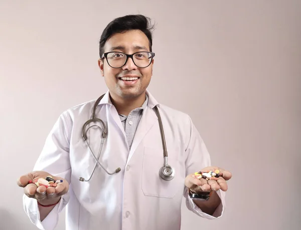 Médico indiano macho de casaco branco e estetoscópio com comprimidos de medicamentos cápsulas na mão — Fotografia de Stock