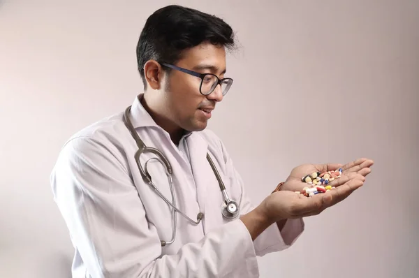 Medico indiano maschio in camice bianco e stetoscopio con pillole medicinali compresse capsule in mano — Foto Stock