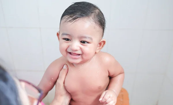 Um bebê recém-nascido inocente índio bonito em um humor jovial com um sorriso encantador com gotas de água em seu corpo durante o chuveiro — Fotografia de Stock