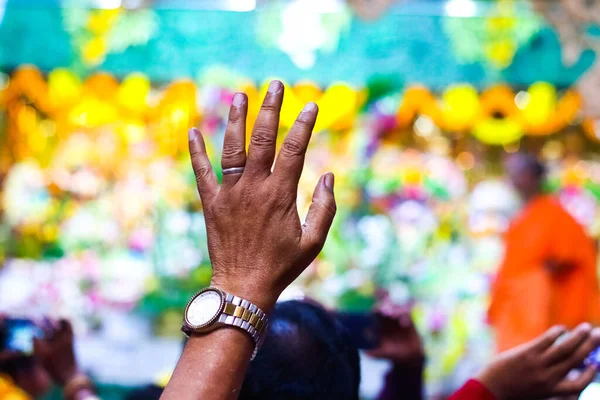 Um devoto levantando as mãos em um templo com fundo turvo e foco seletivo — Fotografia de Stock