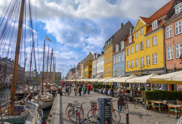 People stroll the cobblestone streets of Nyhavn area in Copenhagen Denmark