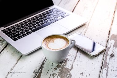 Yan görünümü laptop ile cep telefonu ve bir fincan taze kahve latte sanat ahşap tablo