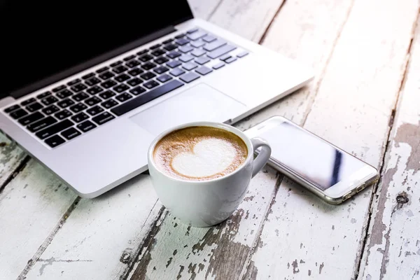 Yan görünümü laptop ile cep telefonu ve bir fincan taze kahve latte sanat ahşap tablo