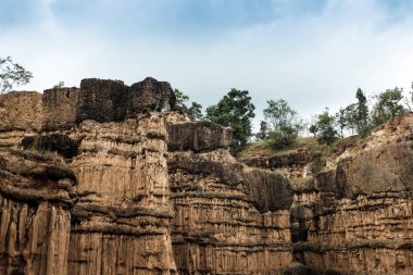 Ağaçların altında Tayland bulutlu gökyüzü yakınındaki kum garip şekiller uçurum