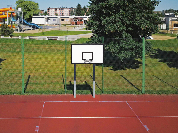 Modern basketball court in the courtyard of primary school. Multifunctional children's playground with artificial surfaced fenced with mesh fence.Place of physical education of children and young.