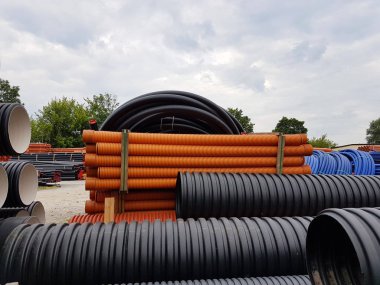 A warehouse of plastic pipes for various purposes, diameter and color under the open sky. Manufacture and sale of plastic products for construction works.om plastic. Drainage and sewerage.  clipart