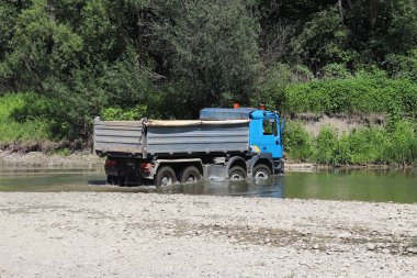 Bir kamyon bir sığ dağ nehri geçerken. Yerlere ulaşmak zor ve tehlikeli koşullar malların taşınması. Ekoloji çevre. Su üzerinde bekletin. Nehrin bir bölgedir