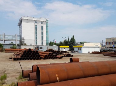 Bir ambar açık havada irili ufaklı metal boru. İnşaat sektörünün teknolojileri. Güzergah boyunca basınç altında sıvı taşıma. Kazı için metal parçalar.