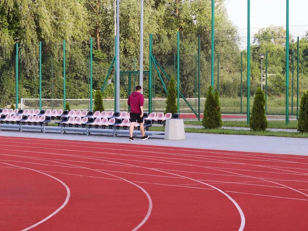 Kırmızı koşu bandı üzerinde futbol sahası. Açık stadyum spor yarışmaları için. Etkin ve sağlıklı bir yaşam tarzı. İleri hareketi. Olimpiyat yarışmalar. Nüfusun boş zaman. Yol işaretleme.