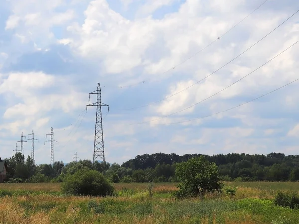 Fırtınalı bir gökyüzü, bulutlar çerçevede bir güneş tarafından aydınlatılmış bir yüksek voltajlı güç hattı. Enerji uzun mesafelere taşınması. Modernliğin yüksek teknoloji. Güç endüstrisi. Ekoloji.