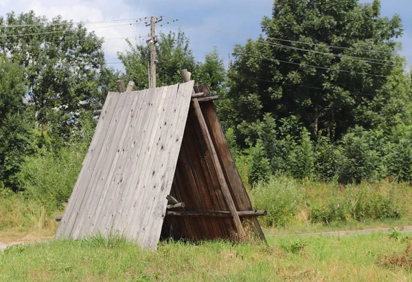 Wooden hut in the green for a holiday in the hike. Primitive shelter of rain and sun for scouts, hunters and shepherds. Romance of travel in the wild. Construction of dry wooden boards