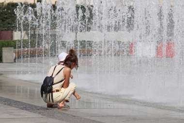 Anne ve çocuk yaz şehir havuzun serinletici sıçramalarına yakın. Banyo ve dinlenme gökkuşağı ışınlarının serbest zaman yaz tatilinde içinde. Tasarım iyileştirme m