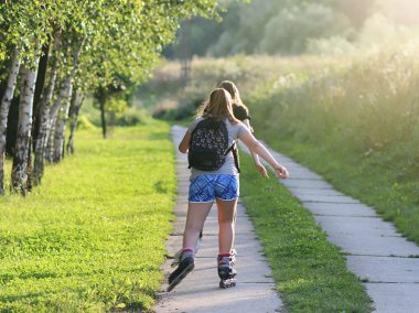 Yaslo, Polonya - 9 Temmuz 2018: roller arasında güneş ışınları yeşillik üzerinde rulo iki kız. Sağlıklı yaşam biçimi ve şekil için bakım. İlave kilogram kilo kaybı. Sabah koşu.