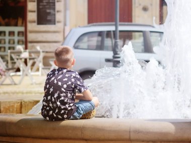 Krosno, Polonya - 9 Temmuz 2018: küçük çocuk ikindilerde şehir Çeşme oturuyor. Neşeli ve tasasız çocukluk şehir. Genç kuşak eğitim. Sprey ve su jet ferahlatıcı