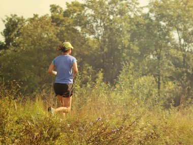 Yaslo, Polonya - 9 Temmuz 2018:A Genç kız çim yeşil güneşin ortasında boyunca çalışır. Sağlıklı yaşam biçimi ve şekil için bakım. İlave kilogram kilo kaybı. Joggig sabah çalışması.