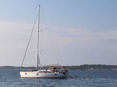 Modern Yelkenli Yat bir koyda demirlemiş olan. İnsanlar denizde yıkarım. Akdeniz Bölgesi Adriyatik Denizi üzerinde aktif dinlenme. Dalmaçya riviera Hırvatistan. Prestijli ve zengin yaşam tarzı