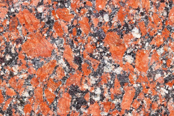 The background of polished granite in red black shades. A background for design and creative work. Decoration and exterior decoration of the building. Construction works.