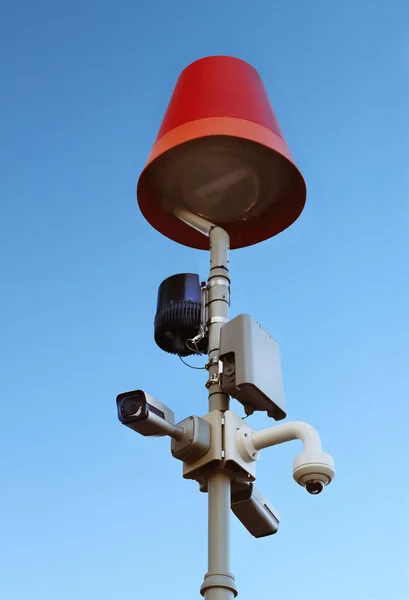Surveillance system with an orange warning light located on a pole in the open. The threat of privacy and the protection of personal data. Security tracking on the streets of the city. Human mass mana