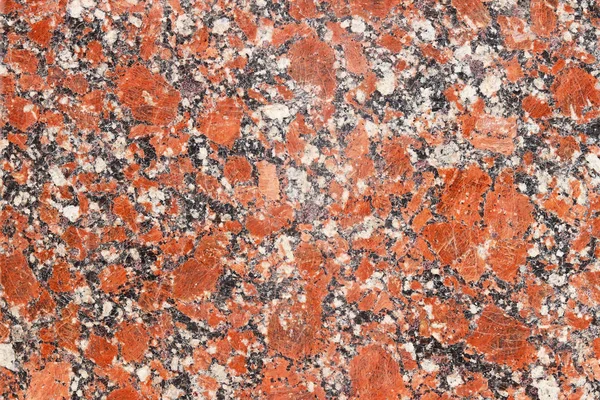 The background of polished granite in red black shades. A background for design and creative work. Decoration and exterior decoration of the building. Construction works.