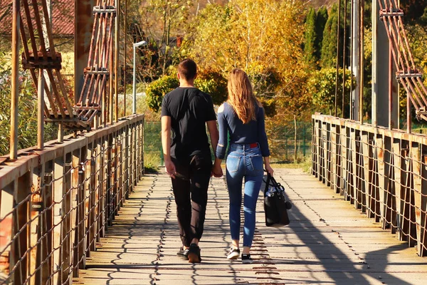年轻夫妇 男孩和女孩走在桥上的秋天牵手 浪漫男人和女人之间的关系 人们之间的爱的表现 在清新的空气中行走 常见方式 — 图库照片